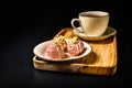 Three truffle candies in pink chocolate glaze on a round saucer. A cup of coffee in the background.