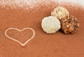 Three truffle candies on a white table sprinkled with cocoa.