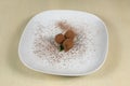 Three truffle sprinkled with cocoa on a white plate