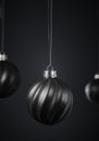 Three twisted striped black Christmas balls against dark gray background