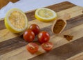 three and two half of cherry tomatoes with half lemon lemon slice and scoop with red pepper spice on wooden cutting board Royalty Free Stock Photo