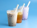 Three Different Types of Boba Tea on a Bright Blue Background