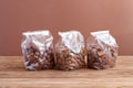 Three types of nuts - hazelnuts, almonds, pecan nuts - in transparent bags on a wooden table against a brown wall. Closeup Royalty Free Stock Photo