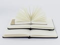 Three unfold notebooks lie on top of each other. Pyramid of books. Small fan open notepad with blank light beige pages.