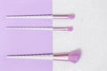Three unicorn makeup brushes on silver violet