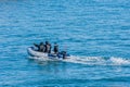 Three unidentified people in rubber dinghy on blue ocean Royalty Free Stock Photo