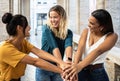 Three united multiethnic young women friends stacking hands outdoors Royalty Free Stock Photo