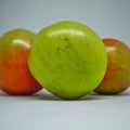 three unripe but fresh looking tomatoes on a white background