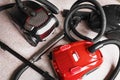 Three vacuum cleaners in different colors sitting on a white carpet floor. Royalty Free Stock Photo