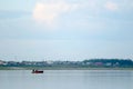 Three vague silhouettes of people of the Northern Yakuts on a boat with oars floating across the river Viluy