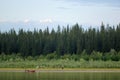 Three vague silhouettes of people of the Northern Yakuts on a boat with oars floating across the river vilyu