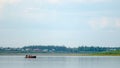 Three vague silhouettes of people of the Northern Yakuts on a boat with oars floating across the river vilyu from shore to shore