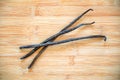 Three vanilla pods with a flower on wood Royalty Free Stock Photo