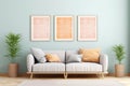 Three vertical picture frames with orange textured art in a modern living room with white sofa, pillows and plants. Pastel green Royalty Free Stock Photo