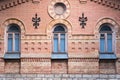 Three vintage arched windows in a wall of yellow bricks. Green - the colors of sea wave glass in a maroon dark red Royalty Free Stock Photo