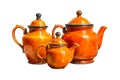 Three vintage orange ceramic teapots of varying sizes isolated on a white background showcasing antique kitchenware and Royalty Free Stock Photo