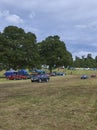 Three Vintage Triumph Cars being driven across the Show Field at the Strathmore Vintage Vehicle Show.