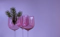 Three vintage wine glasses made of pink glass with a fir twig on a lilac background. The concept of Christmas and New Royalty Free Stock Photo