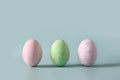 Three violet decorative pastel eggs. Happy Easter greeting card with copy space. Top view.