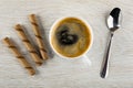 Three wafer rolls with chocolate filling, black coffee in cup, spoon on wooden table. Top view Royalty Free Stock Photo