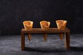 Three waffle cones waiting to be filled with ice cream on dark background