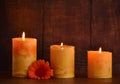 Three wax orange candles and gerbera flowers Royalty Free Stock Photo