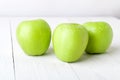 Three wet green apples on white wooden background. Royalty Free Stock Photo