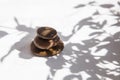 Three stones are stacked one on top of the other in the shadows of leaves and sunlight on a white marble background Royalty Free Stock Photo