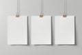 Three white blank posters mockup hanging on paper clip on grey background Royalty Free Stock Photo