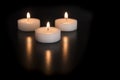 Three burning tea lights on a black background Royalty Free Stock Photo