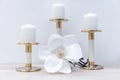 Three white candles on brass candlesticks and a white tropical flower