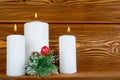 Three white candles with pine brunch