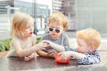 Three white Caucasian cute adorable funny children toddlers sitting together sharing food.