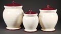 three white ceramic jars with red lids on a gray background with a black background and a black background with a white