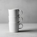 Three white ceramic mugs are stacked vertically on a textured gray surface, with Royalty Free Stock Photo