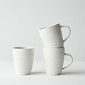 Three white ceramic vessels are shown against a plain background. One is a straight- Royalty Free Stock Photo