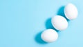 Three white chicken eggs on blue background. Minimal concept. concept of Easter or protein food. Close-up Royalty Free Stock Photo