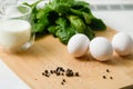 Three white chicken eggs on a cutting board with a bunch of fresh spinach Royalty Free Stock Photo