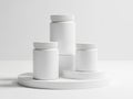 Three white cylindrical containers with lids on a circular surface Royalty Free Stock Photo