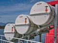 Three white, cylindrical life raft containers in a deployment chute. Taken on a CalMac ferry