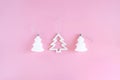 Three white decorative Christmas and New Year trees on a pastel pink background. Royalty Free Stock Photo