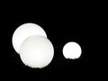 Three white decorative spheres lit up in a garden at night time Royalty Free Stock Photo