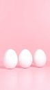 Three white eggs in a row on light pink background, minimal Easter concept for holiday themes, copy space above. Royalty Free Stock Photo