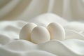 Three white eggs sitting on top of a white cloth Royalty Free Stock Photo