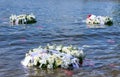 Three white floral memorial wreaths float in Brooklyn Bridge Park