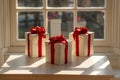 Three White Gift Boxes with Red Ribbons on Window Sill, Sunlight Streaming Through Window Royalty Free Stock Photo