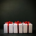 Three white gift boxes together with red bows on black background. Square.