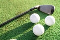 Three white gold balls and a golf club on a green artificial grass field Royalty Free Stock Photo