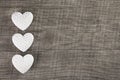 Three white hearts on an old grey brown wooden background.