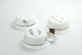 Three white home smoke alarms with a battery